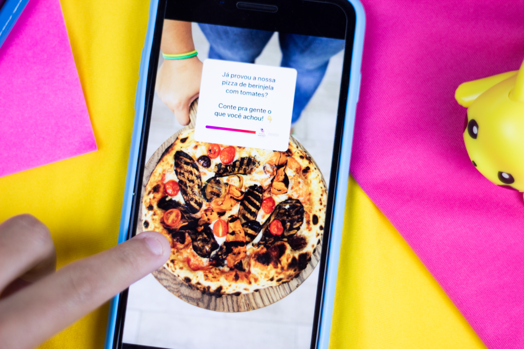 Celular aberto em um story do Instagram com uma foto de pizza e o adesivo de emoji slider