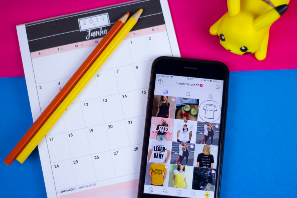 Mesa com calendário, lápis e um celular aberto no Instagram