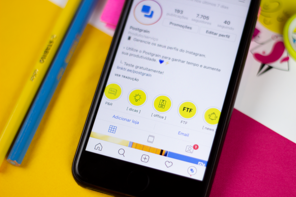 Celular aberto no perfil do Instagram do Postgrain, mostrando os destaques de stories