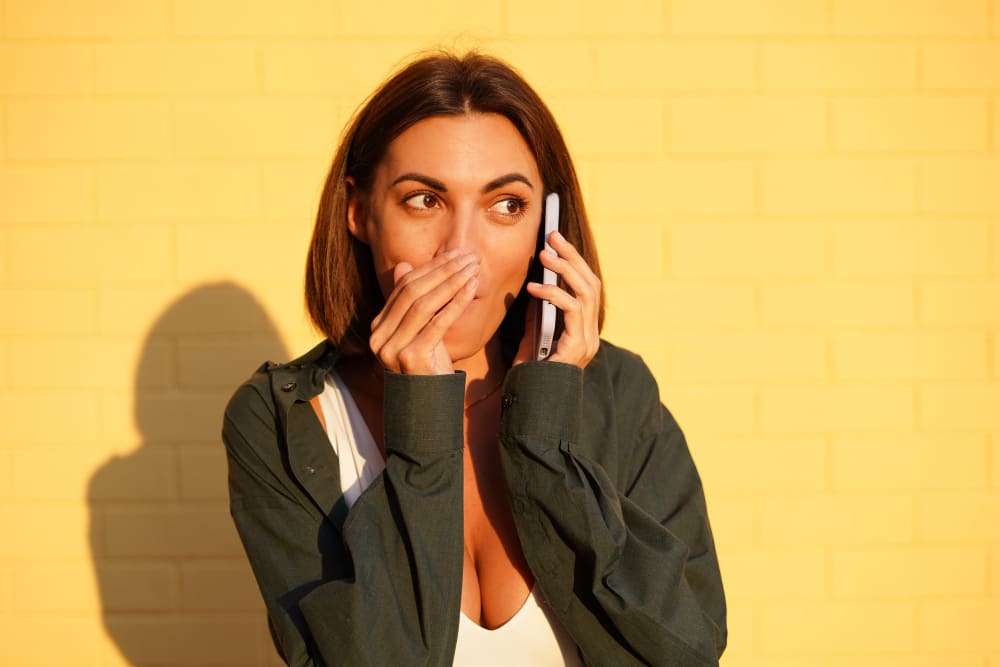 Mulher com a mão entre a boca e o celular falando baixinho enquanto usa o modo temporário do Instagram