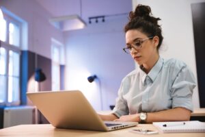 Mulher sentada com o notebook aberto enquanto trabalha 